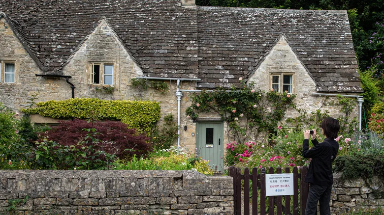 a woman photographing a charming stone cottage