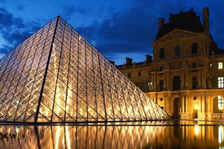 The glass façade of the Louvre at night