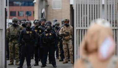 Law enforcement officers watch as the gates close at a U.S. Immigration and Customs Enforcement facility as people protest outside on Oct. 11, 2025, in Portland, Ore. (AP)