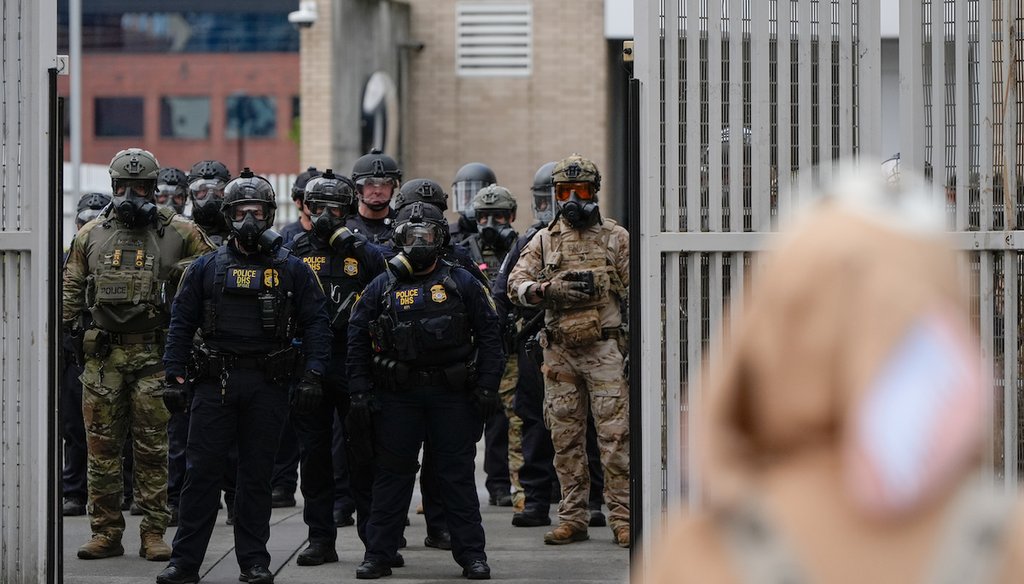 Law enforcement officers watch as the gates close at a U.S. Immigration and Customs Enforcement facility as people protest outside on Oct. 11, 2025, in Portland, Ore. (AP)