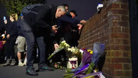PA Media People lay flowers near Midhurst Gardens in Uxbridge.