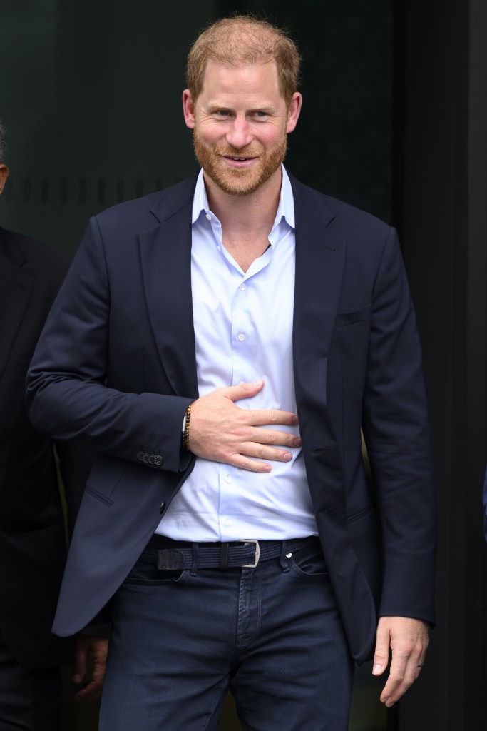 Prince Harry smiling with his hand on his stomach in the UK