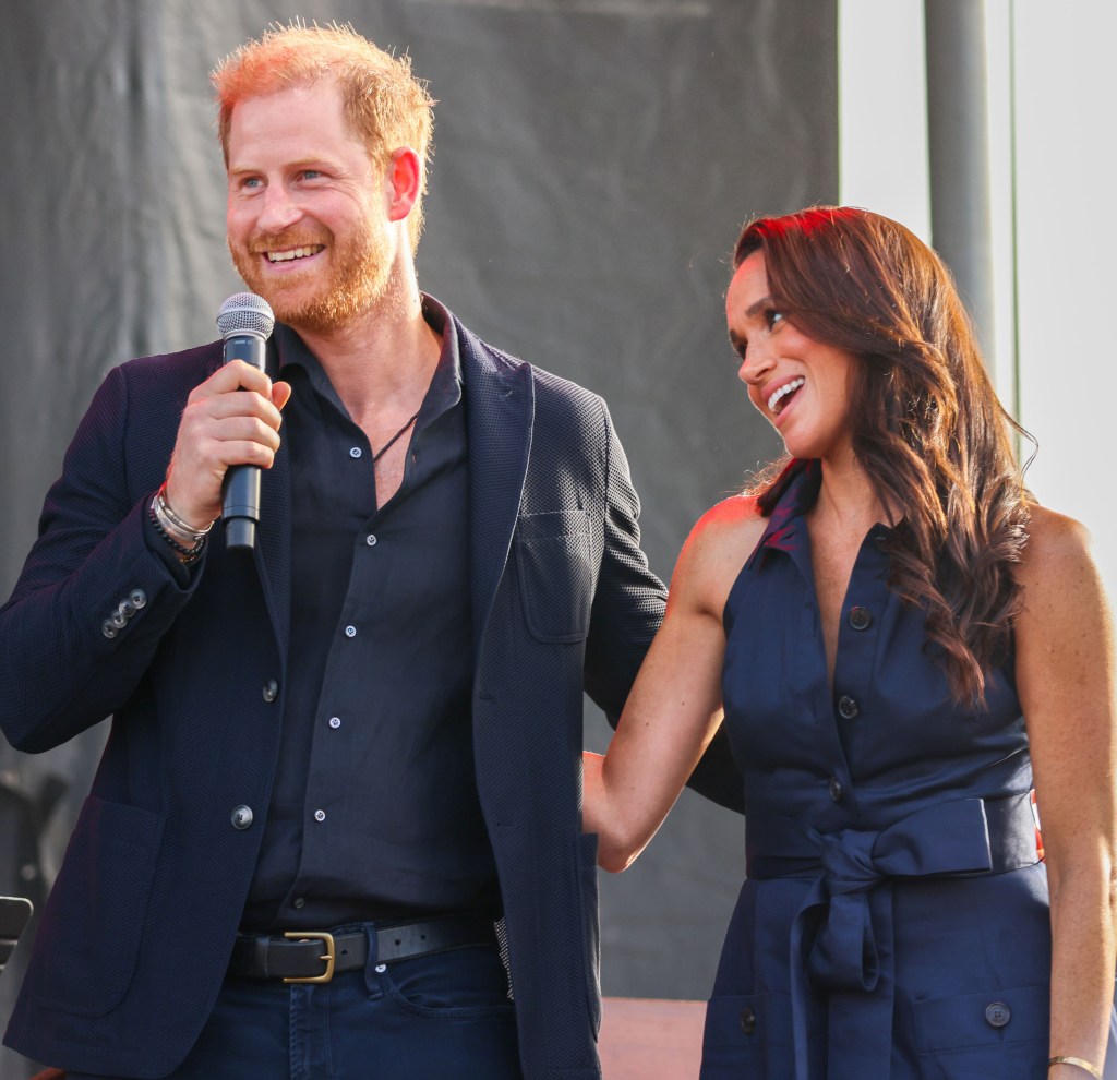 Prince Harry and Meghan Markle smiling and hugging on stage