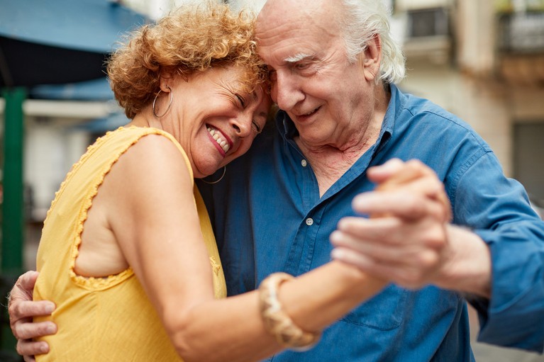 A smiling senior couple dances the tango.