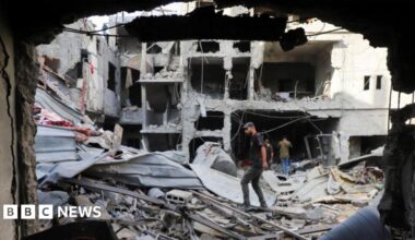 Palestinians look on as smoke rises following explosions in Gaza City, as seen from central Gaza Strip October 5, 2025