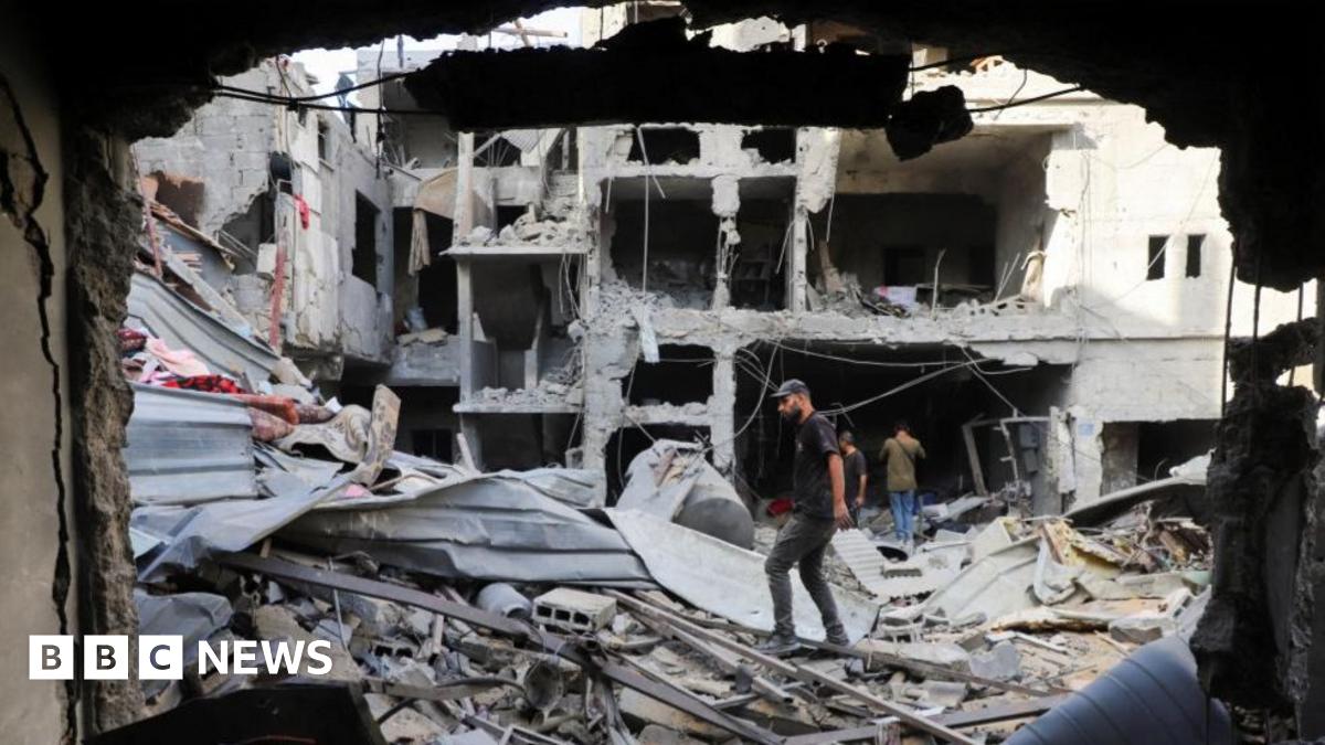 Palestinians look on as smoke rises following explosions in Gaza City, as seen from central Gaza Strip October 5, 2025