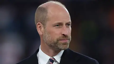 Getty Images Prince William in a dark suit with white shirt and striped tie