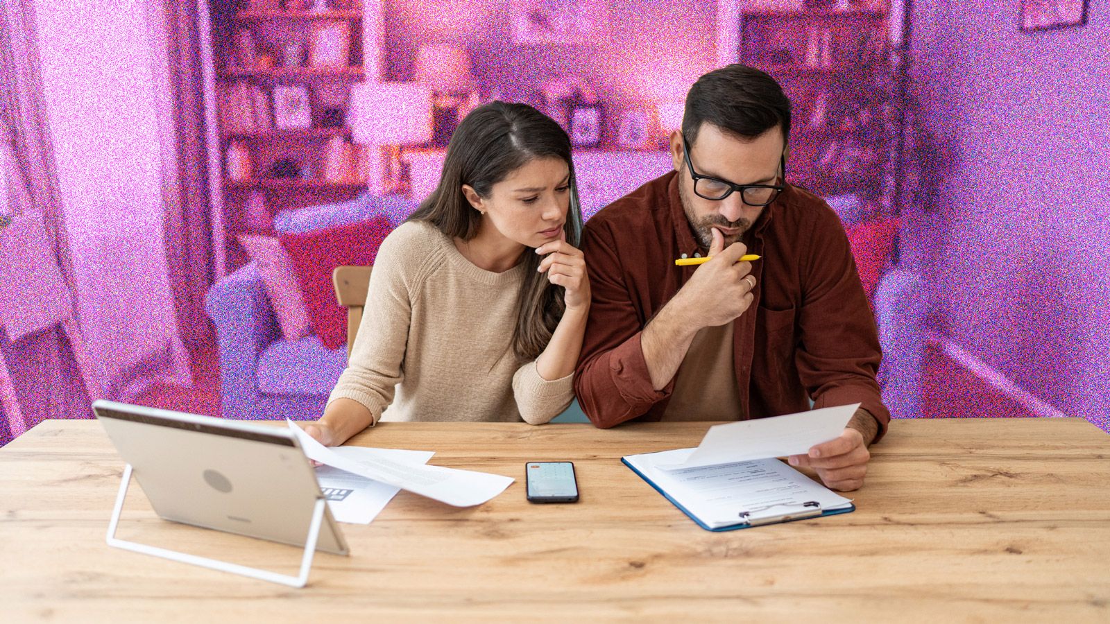 Young couple looking at bills sitting at kitchen table
