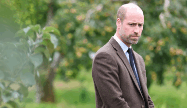 Prince William looking serious in front of an apple tree