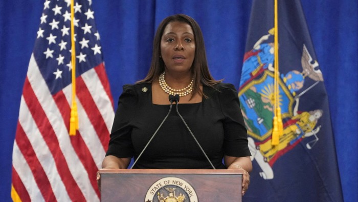 Letitia James speaks at a podium with the New York state seal, flanked by U.S. and New York state flags.