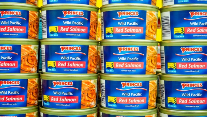 Stacks of Princes Wild Pacific Red Salmon tins arranged on a supermarket shelf, labels facing outward.
