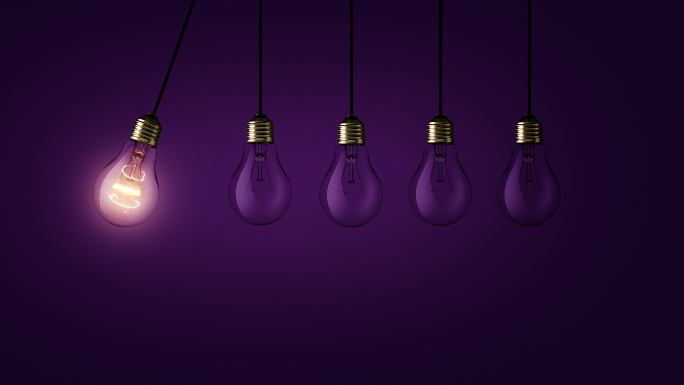Creative light bulb lights up other extinguished light bulbs on a dark purple background, concept. Leadership, creative idea. Think differently. Start up