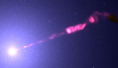 A bright celestial object emits a glowing pink jet of light extending diagonally through space, surrounded by faint stars against a dark background.