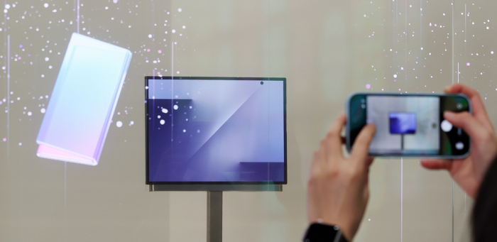 A visitor to the K-Tech Showcase, a side event of the APEC CEO Summit at the Gyeongju Expo Park Air Dome takes a photo of Samsung’s triple-folding smartphone on display