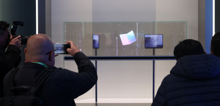 Visitors to the K-Tech Showcase, a side event of the APEC CEO Summit at the Gyeongju Expo Park Air Dome take photos of Samsung’s triple-folding smartphone on display