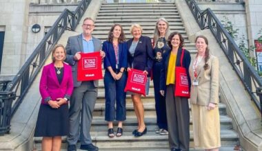 A group of people stand on the steps of a building holding up King