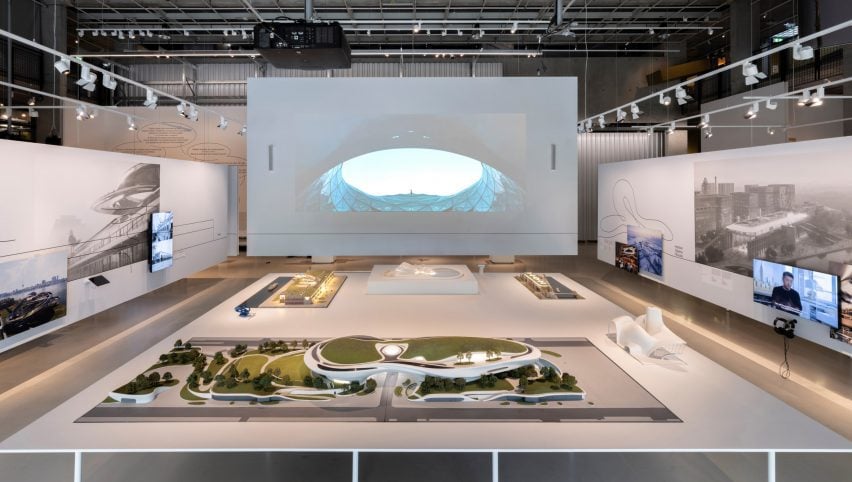 Wide view of the exhibition setup with large-scale models and projection screen