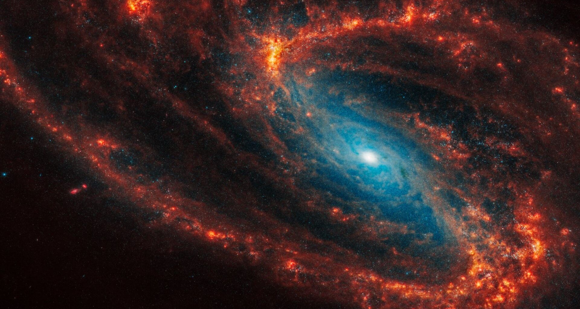 A photo of a spiral galaxy with orange arms and a glowing blue center