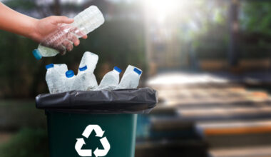 A person throwing plastic bottles in the recycling bin.