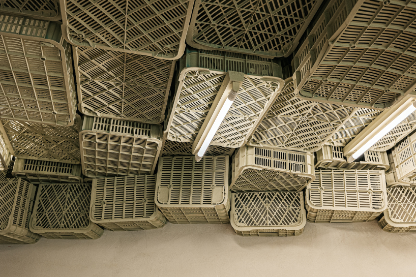 ceiling of recycled plastic crates expands over brutalist supermarket in mallorca