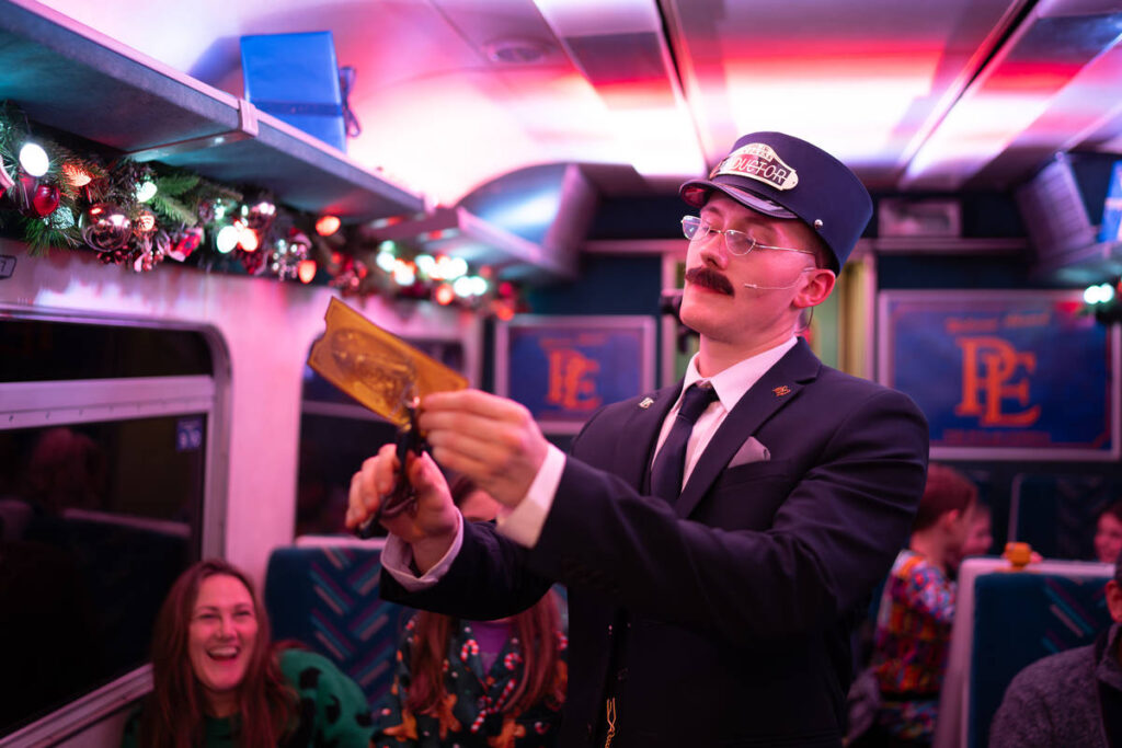 A conducter punching train tickets on board the Polar Express