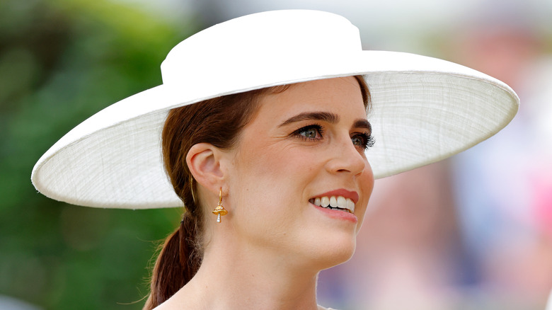 Princess Eugenie smiling in a white, wide-brimmed hat at Ascot 2025