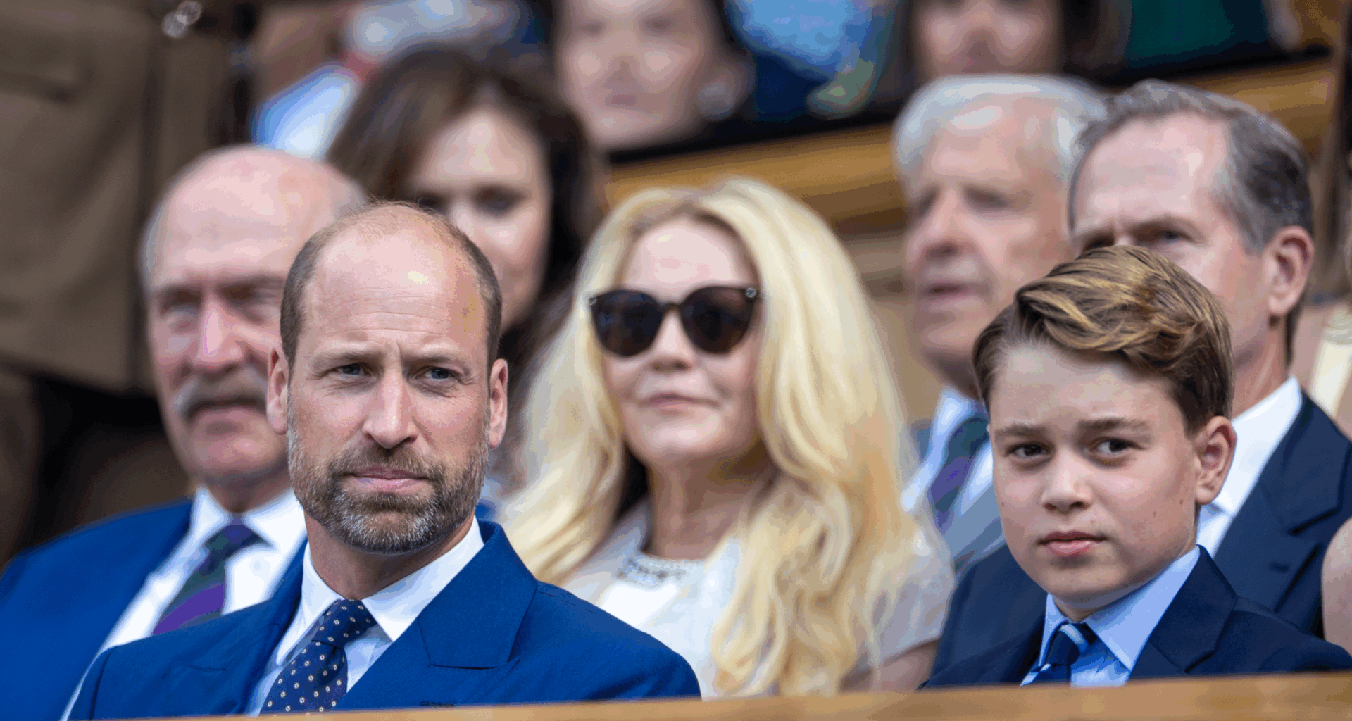 Prince George and Prince William sitting in the stands wearing blue suits at Wimbledon