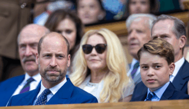 Prince George and Prince William sitting in the stands wearing blue suits at Wimbledon