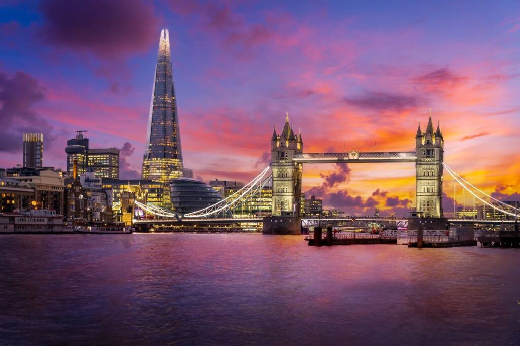 London skyline featuring The Shard, Tower Bridge and River Thames at dusk under a pink and purple sky