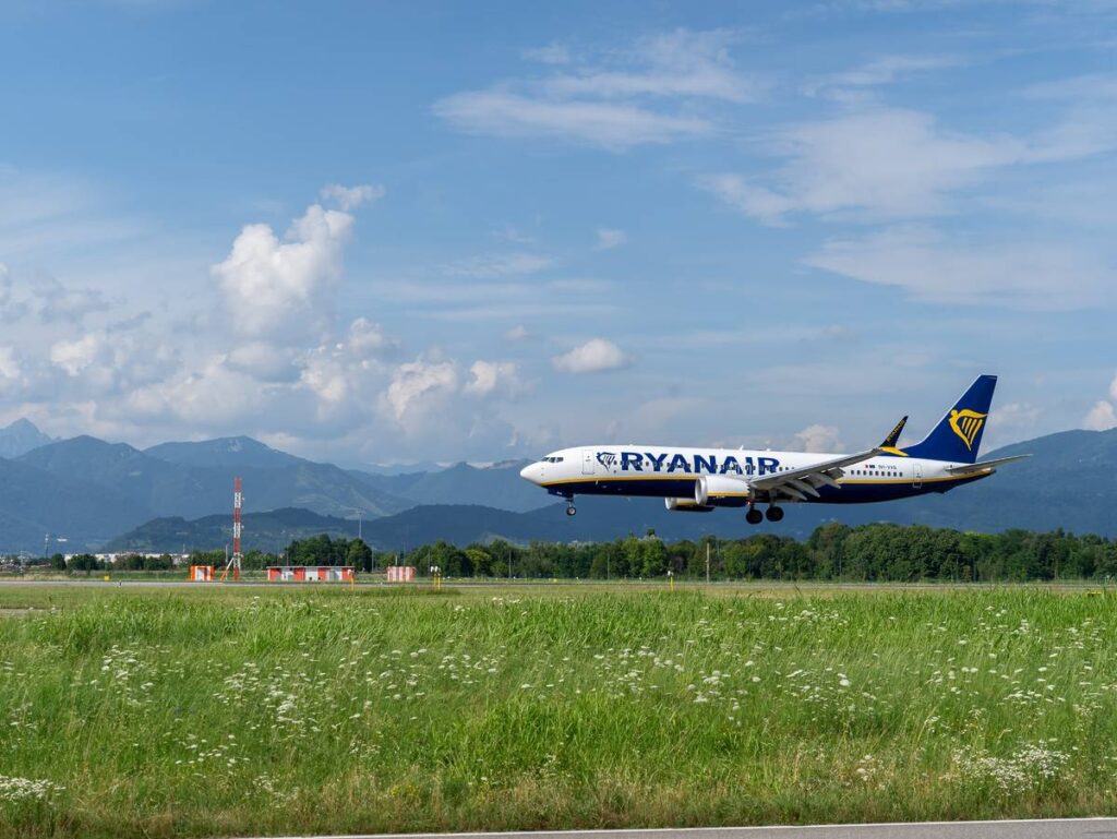 A flight landing on a runway with a blue sky and mountains in the background