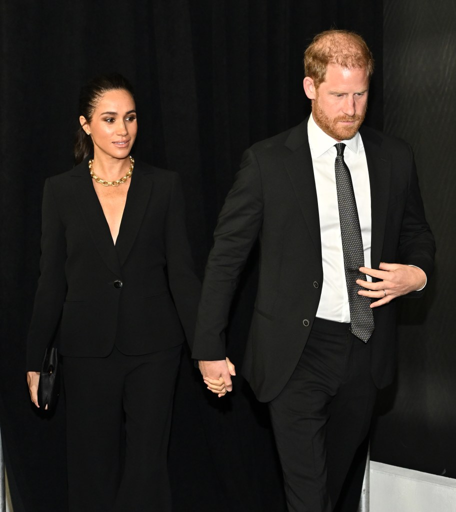 Meghan Markle walking hand-in-hand wearing black suits