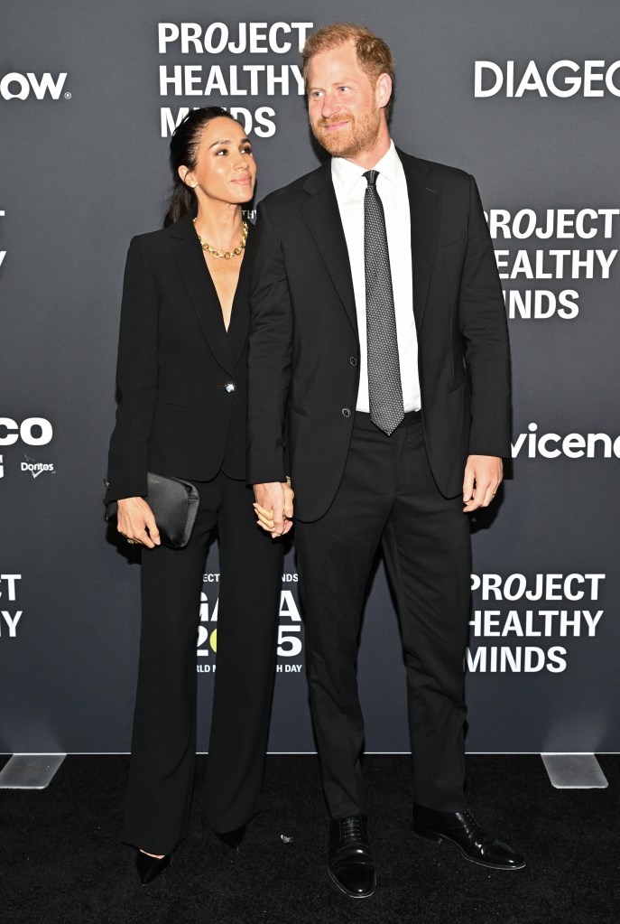 Meghan Markle smiling at Prince Harry on the red carpet at a charity gala