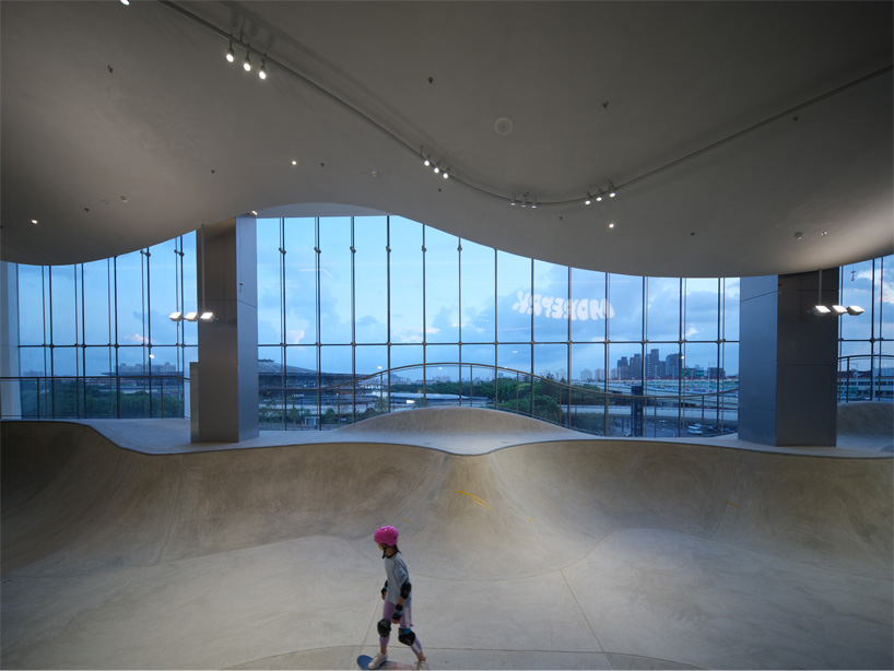 curved urban skatepark set within floating glass volume overlooks shanghai’s skyline