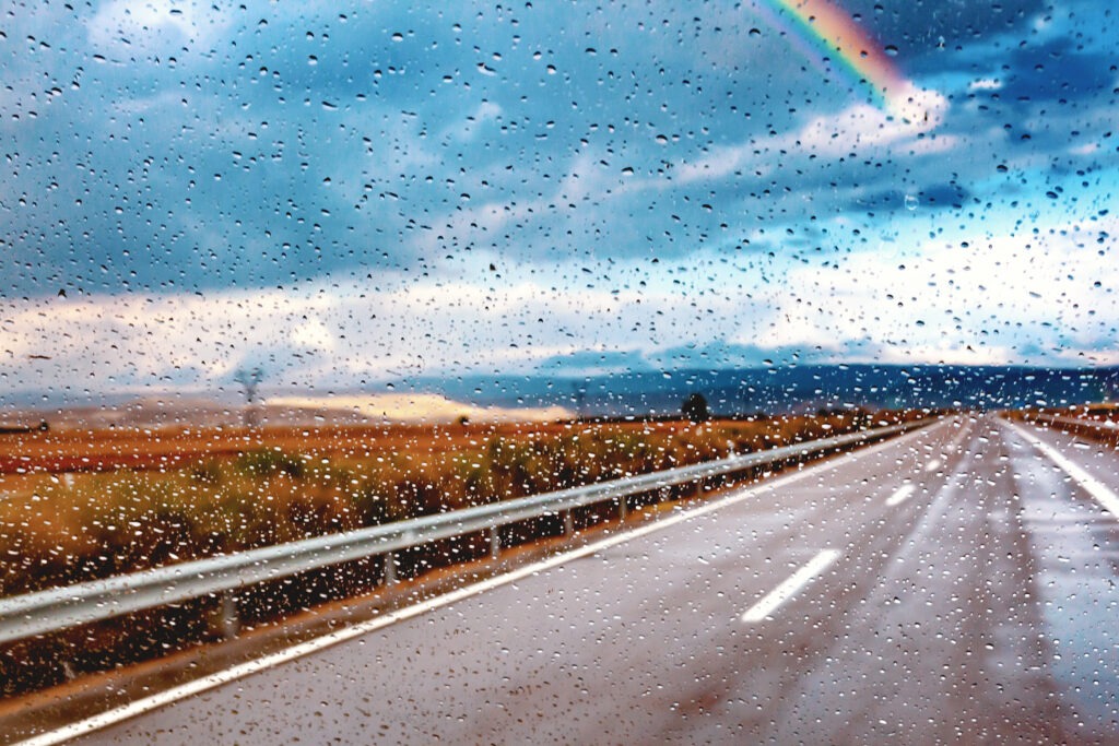 Abstract image of car and road Through the wet window.