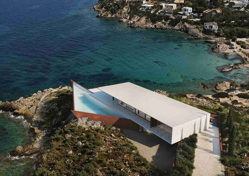 summer residence's sharp geometry emerges from greek seaside slope