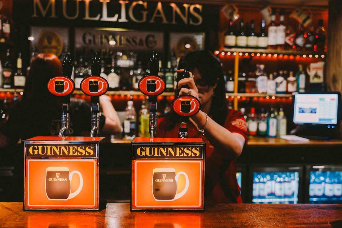 two people pouring pints from guinness taps