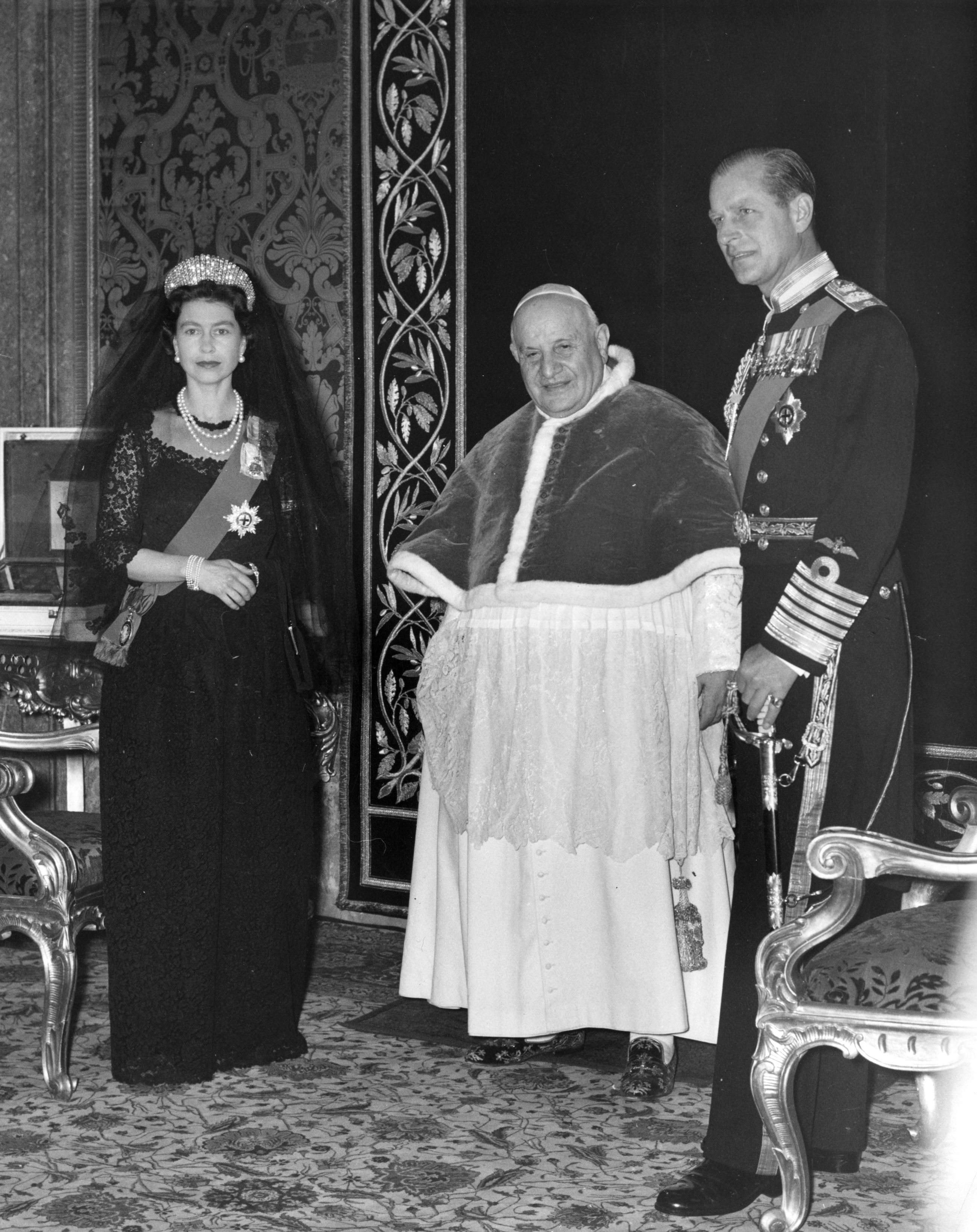 Queen Elizabeth wearing a black veil and dress posing with the Pope and Prince Philip