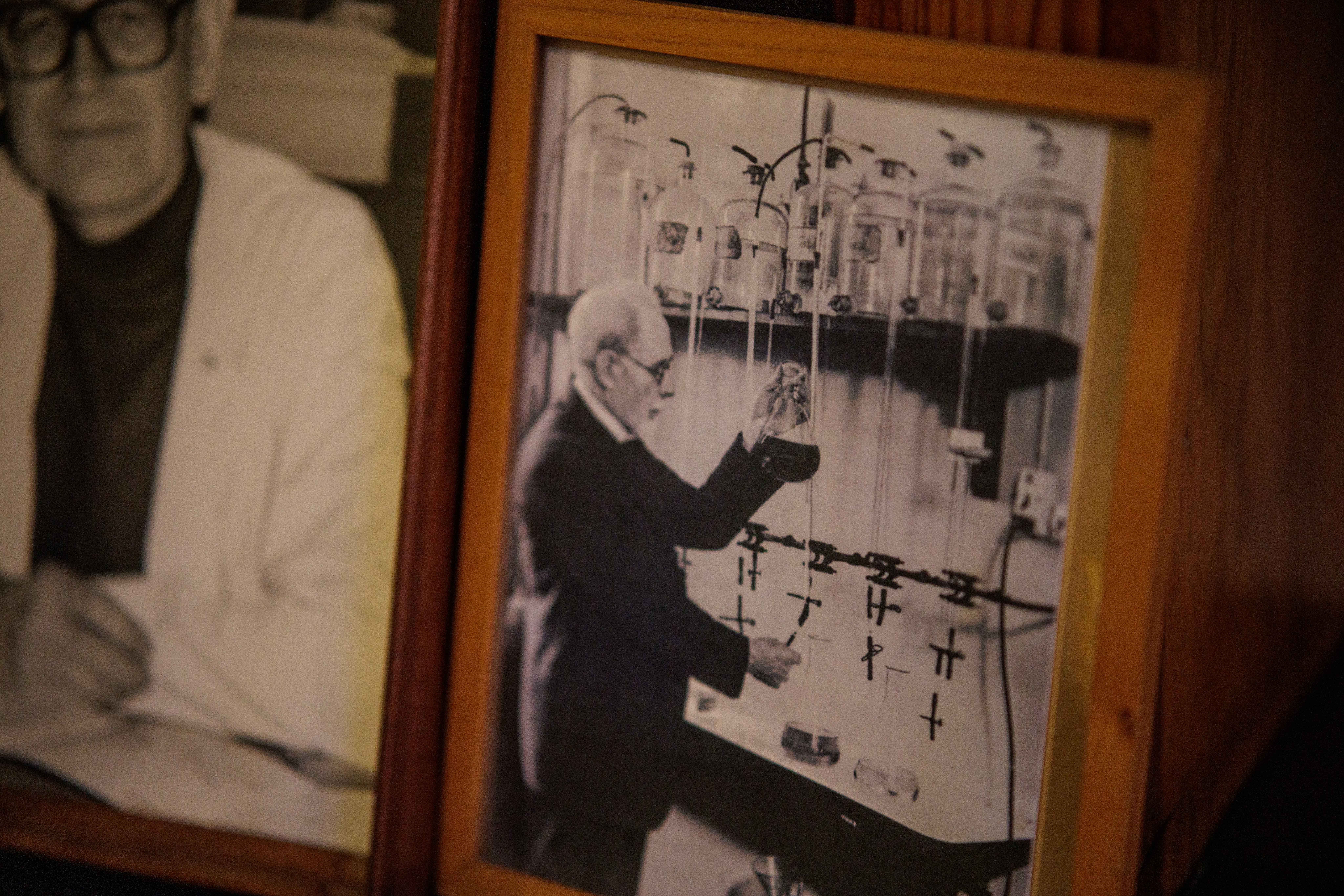 A framed black and white photo of a scientist in a lab, with another blurry photo of a person in the background.