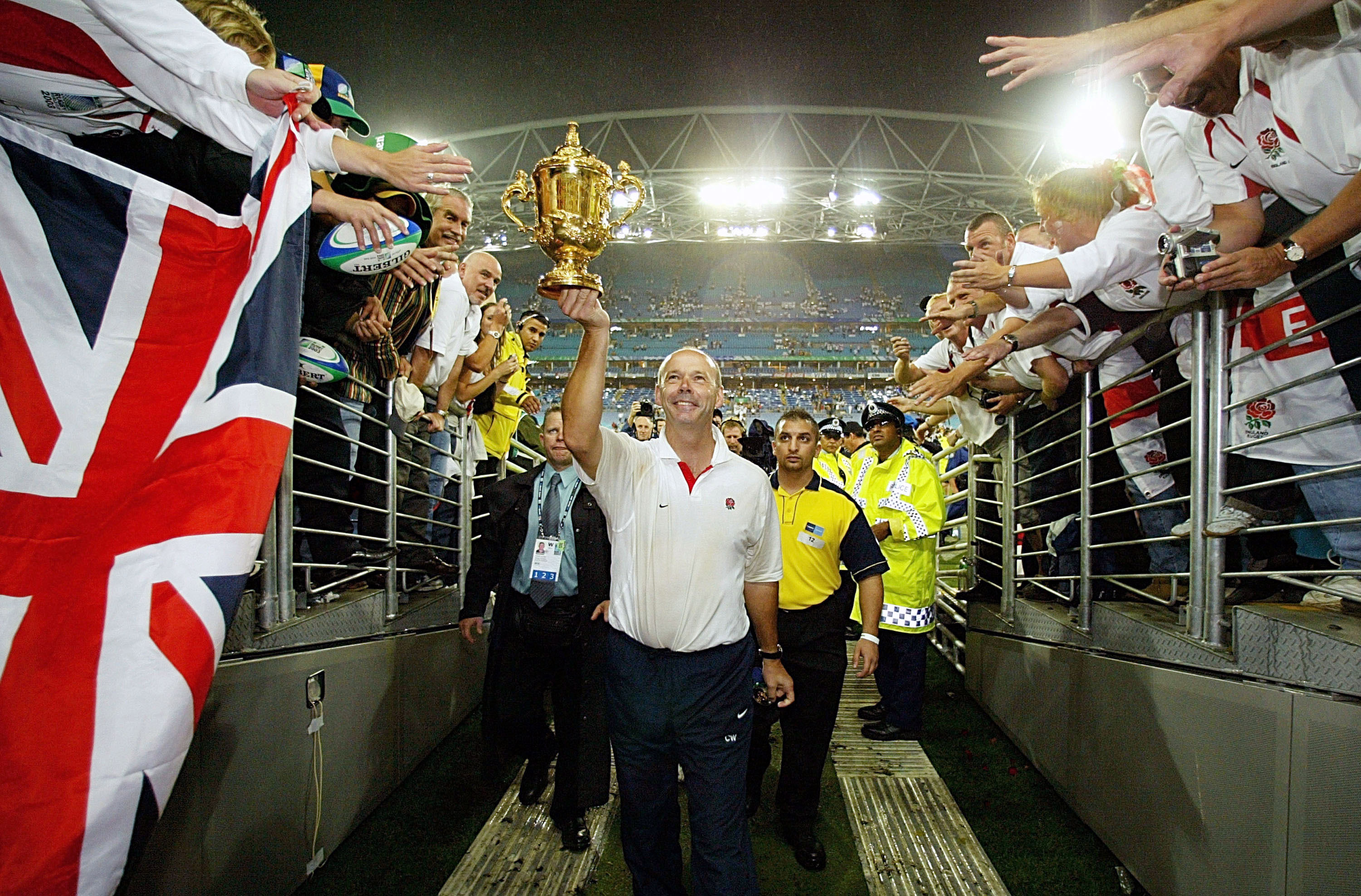 Clive Woodward holds aloft the Webb Ellis cup while leaving the field after England's victory.