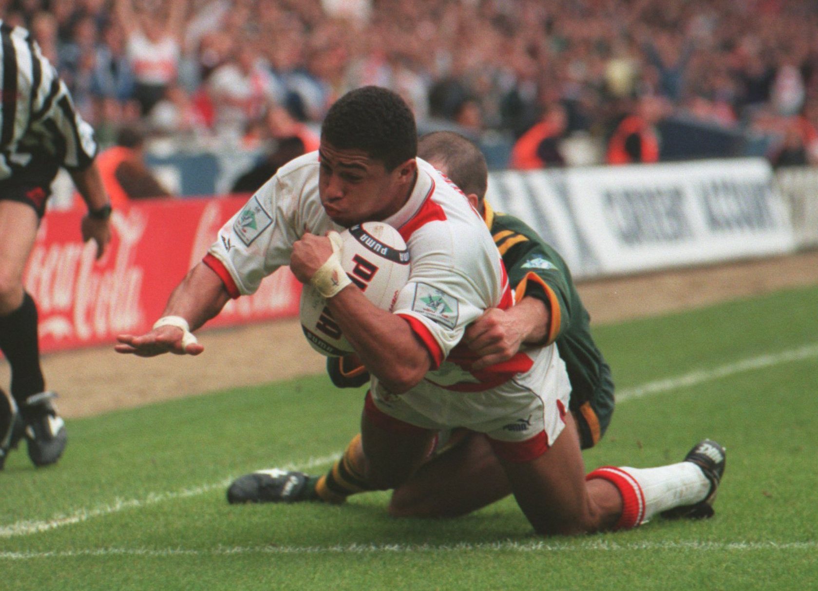 Rugby player Jason Robinson of England scores a try while being tackled by an Australian player.