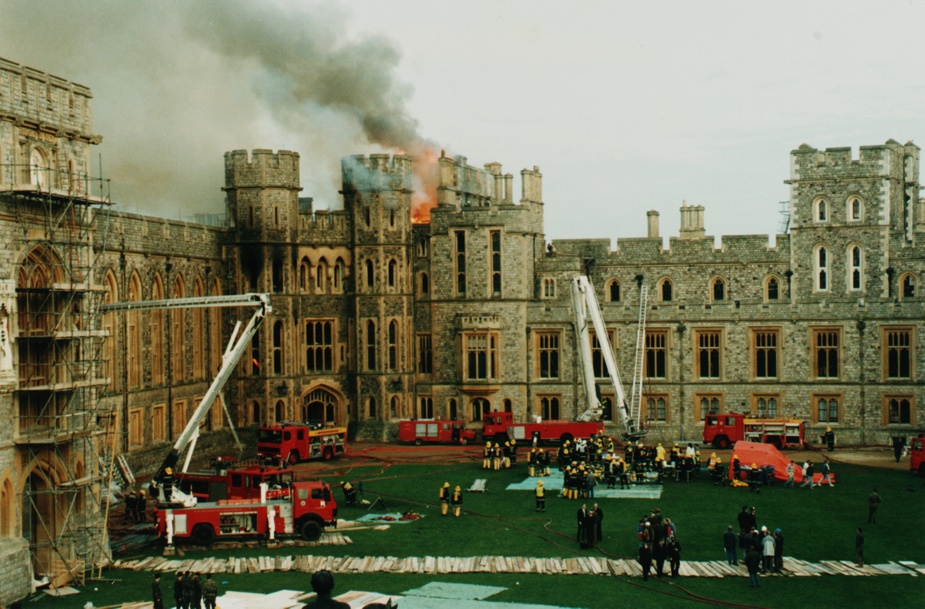 The fire rages at Windsor Castle, with firefighters and firetrucks attempting to extinguish the blaze.