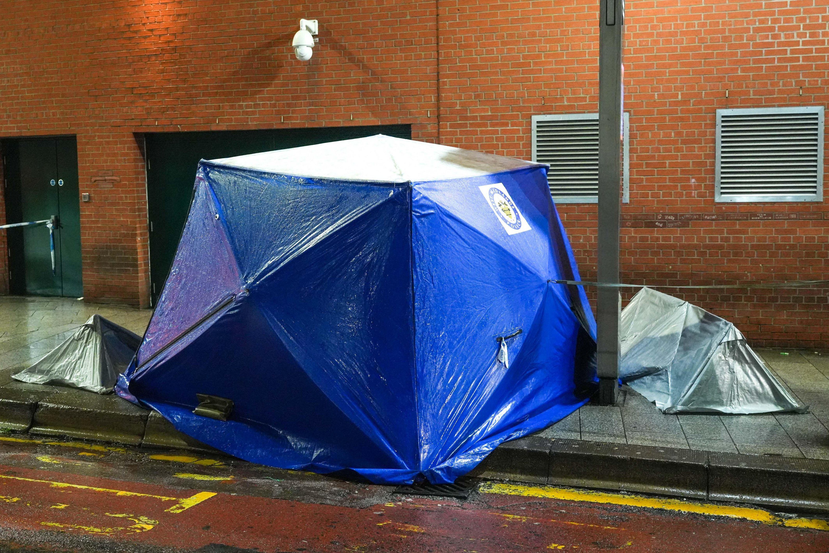 Forensic tents on a sidewalk next to a road, indicating a crime scene.