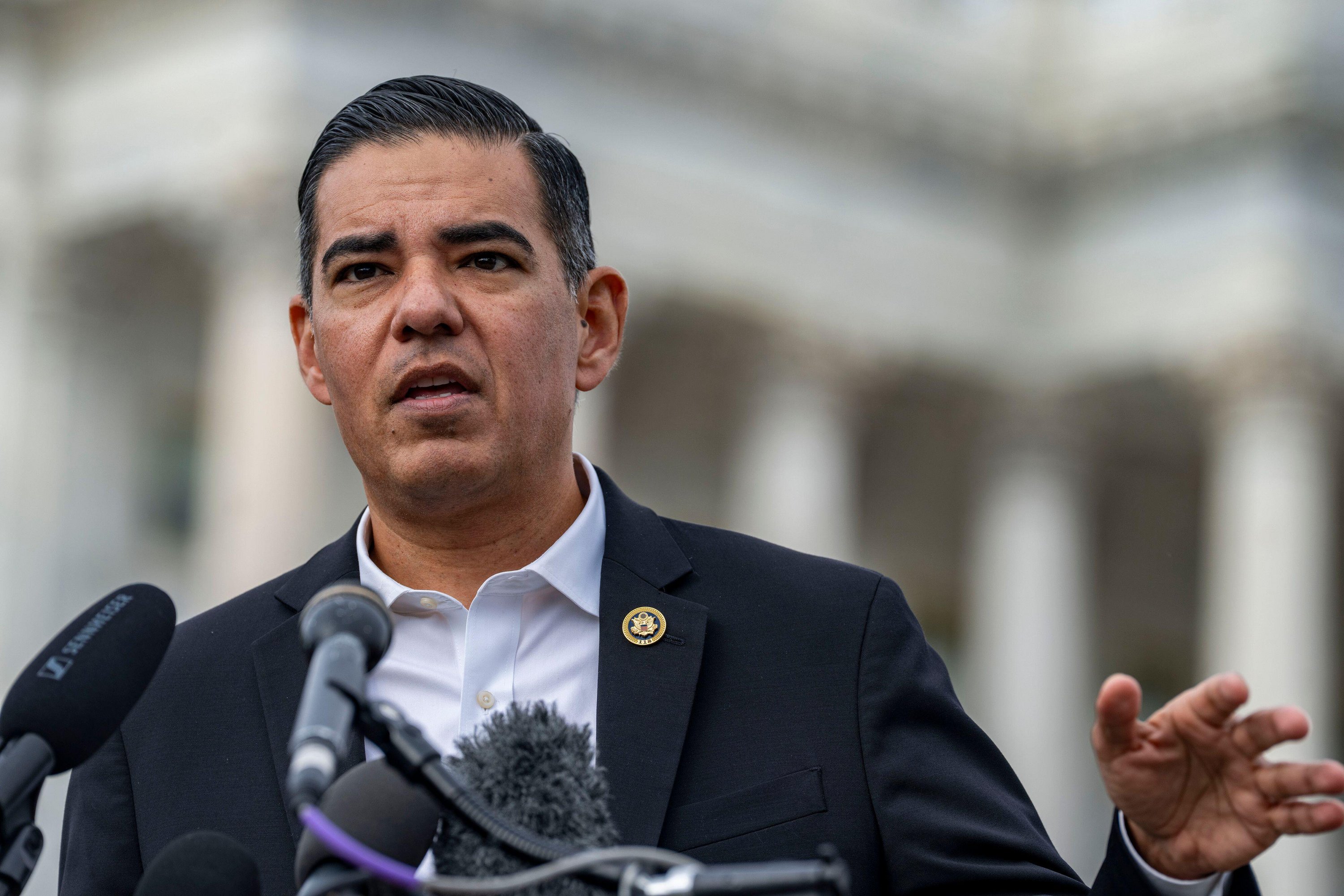 Rep. Robert Garcia speaking at a press conference with microphones in front of him.