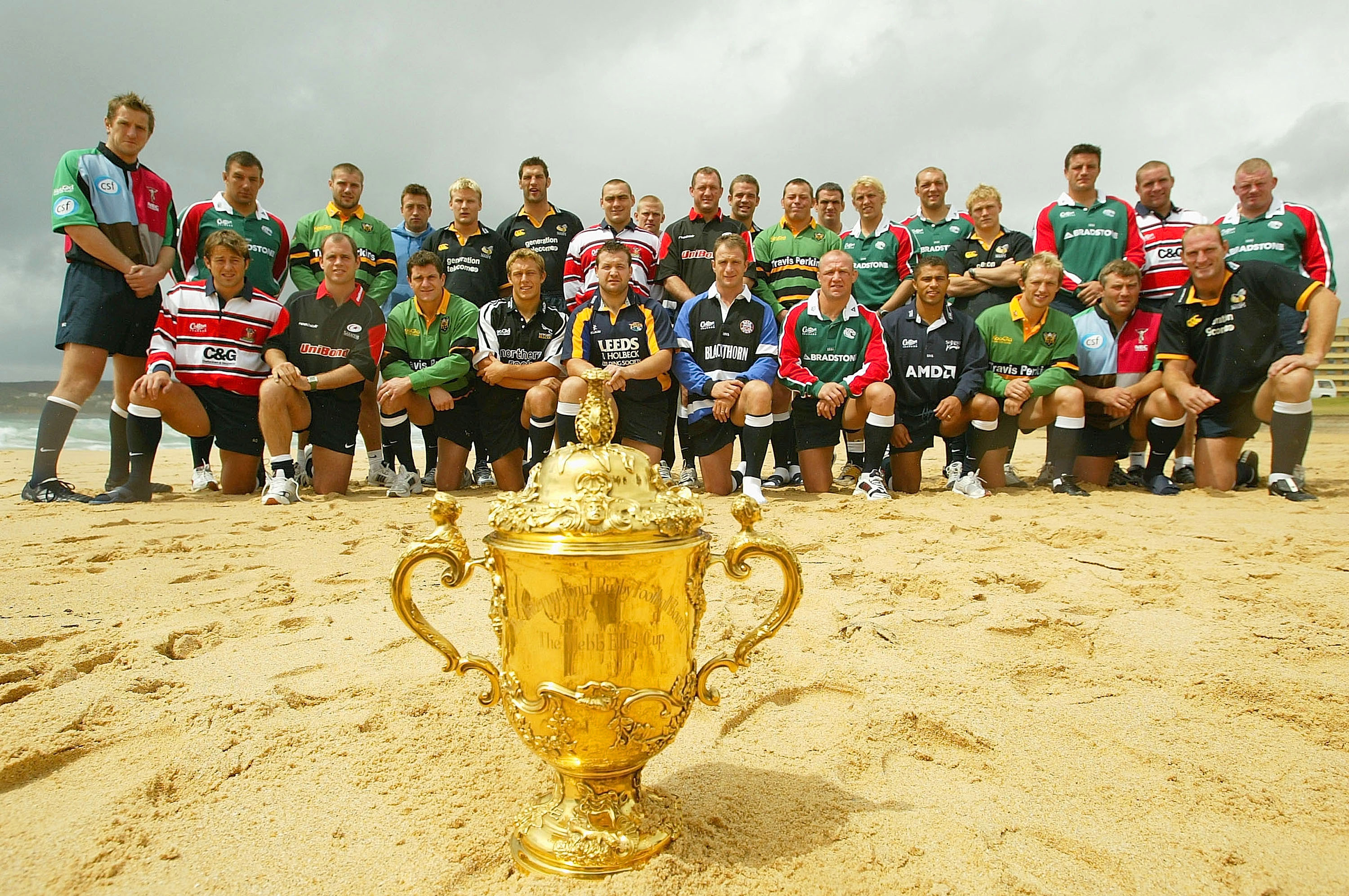 The victorious England rugby squad posing with the William Webb Ellis Trophy on the beach.