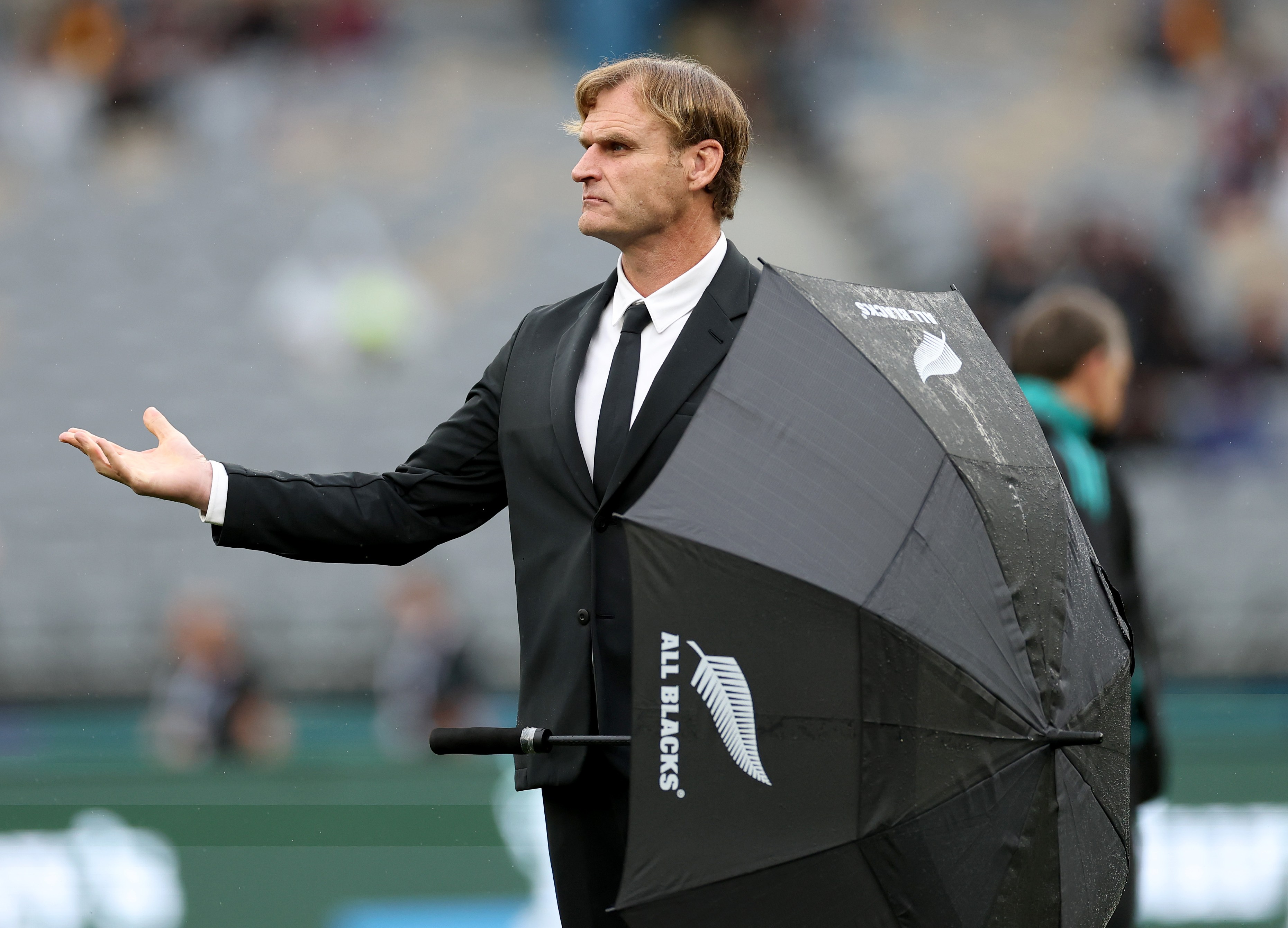 All Blacks head coach Scott Robertson feeling for rain with an umbrella.