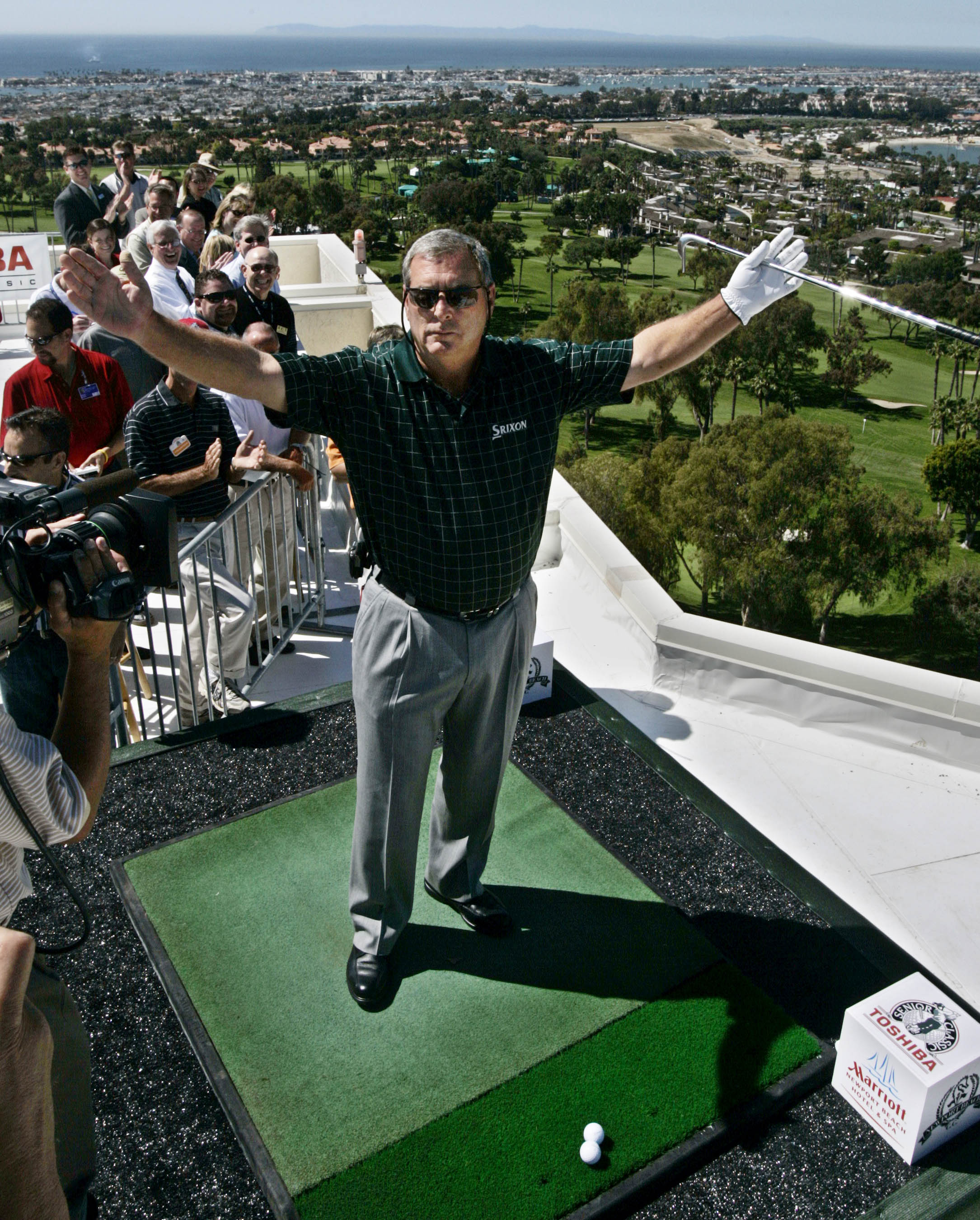 Champions Tour golfer Fuzzy Zoeller celebrates after driving a golf ball from the roof of the Marriott Hotel.