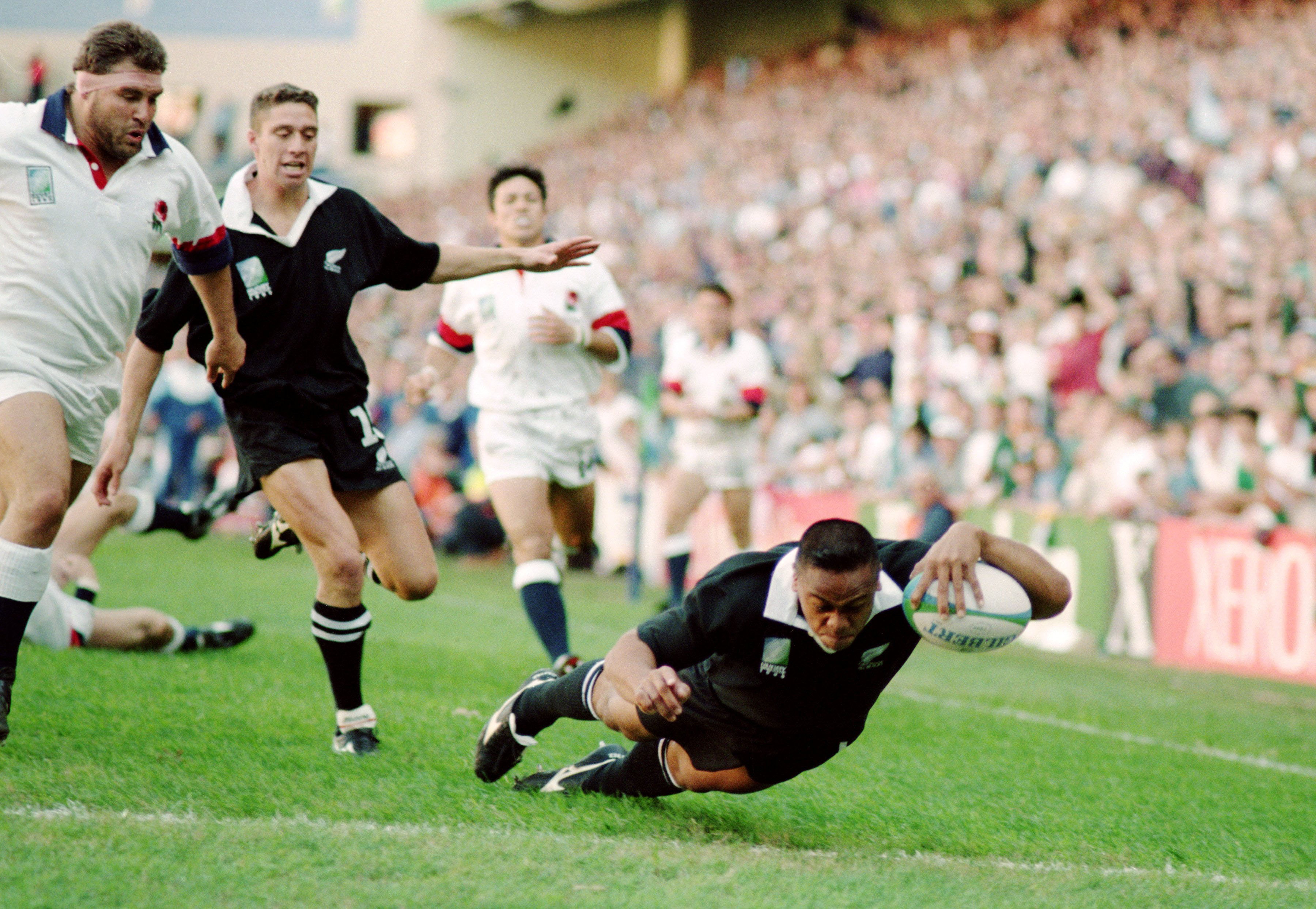Jonah Lomu of New Zealand dives over for a try during a rugby match against England.