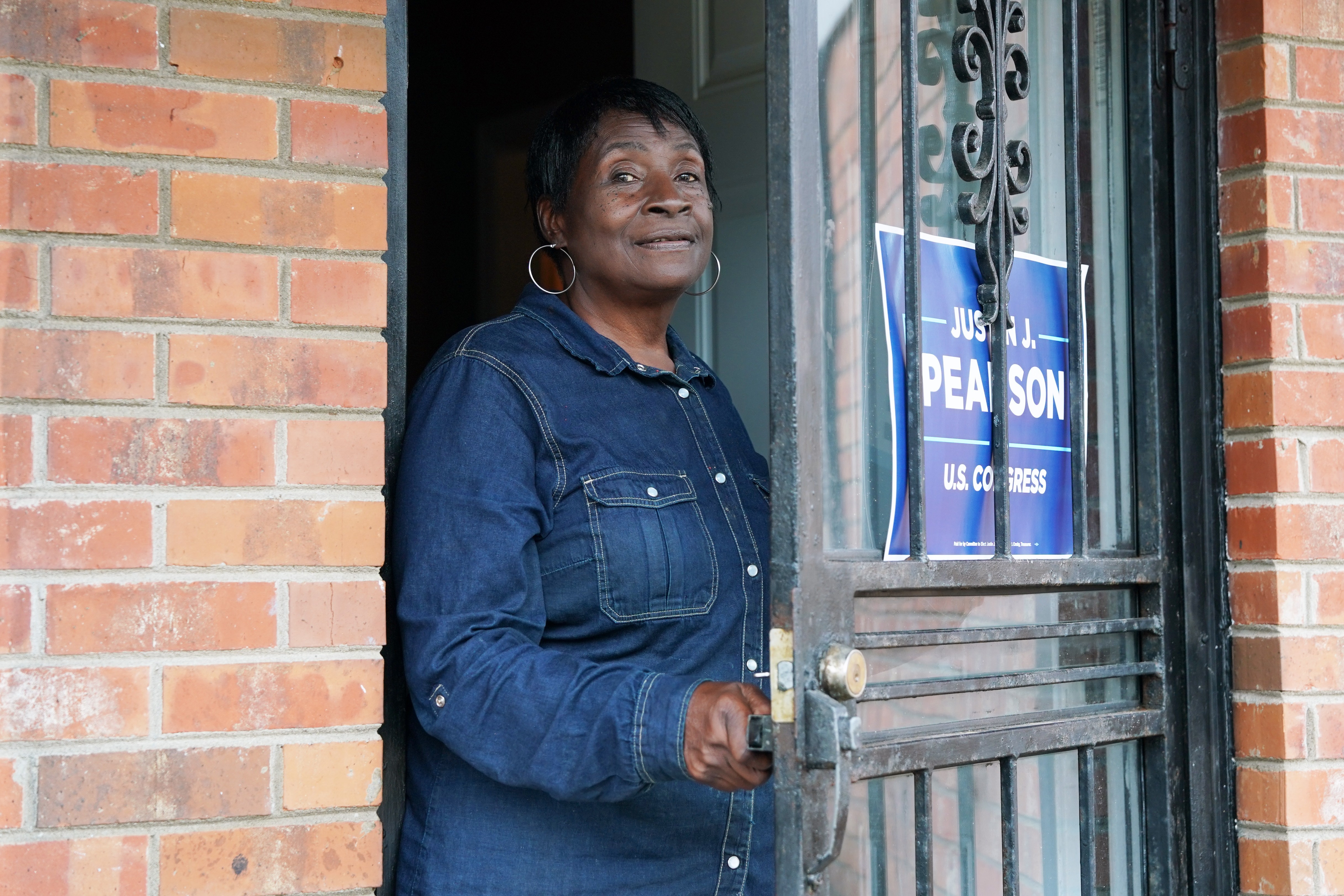 Sarah Gladney opening her front door to speak about the Colossus supercomputer, with a political sign for "Justin J. Pearson U.S. Congress" on her storm door.