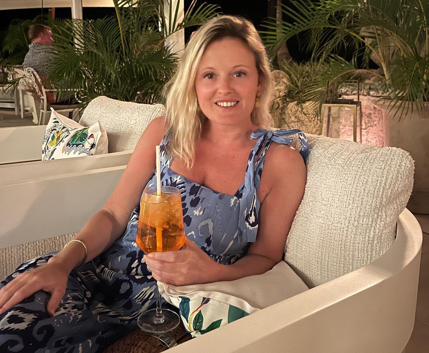 Victoria Bond sitting on an outdoor sofa with a drink.