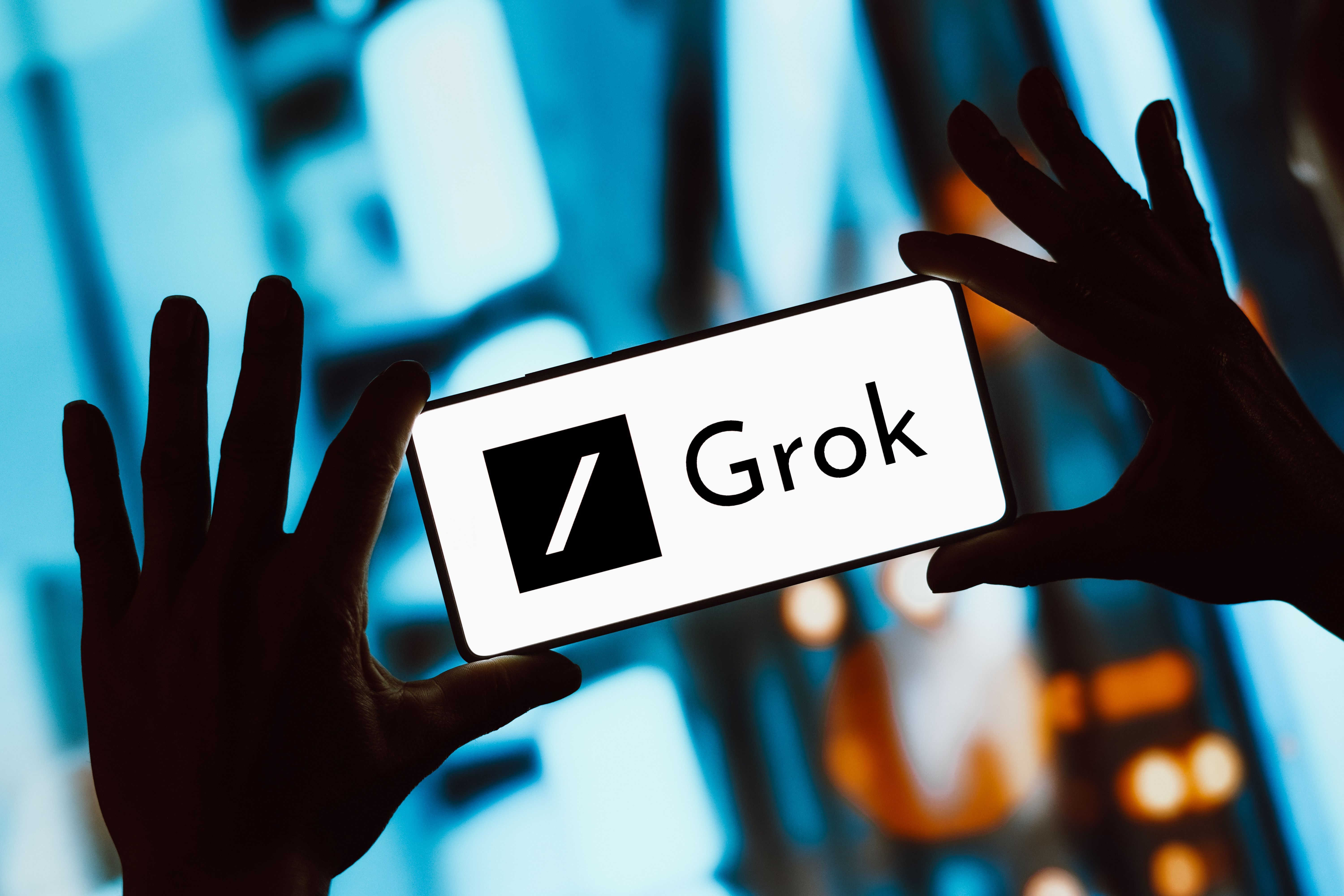 Illustration of hands holding a smartphone displaying the Grok logo.